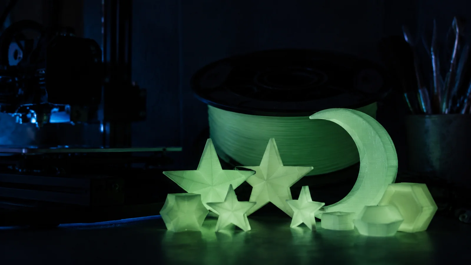 Karanlık atölyede yeşil ışık yayan 3D baskı yıldızlar ve glow filament makarası